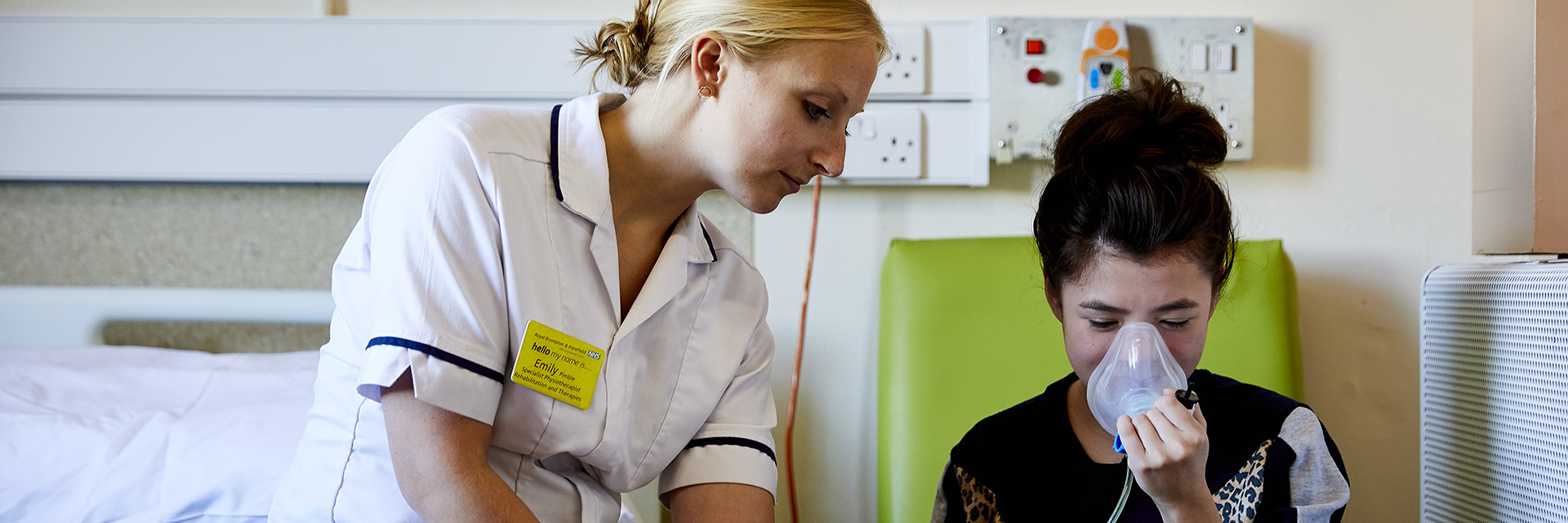 Nurse helps a girl use an oxygen mask