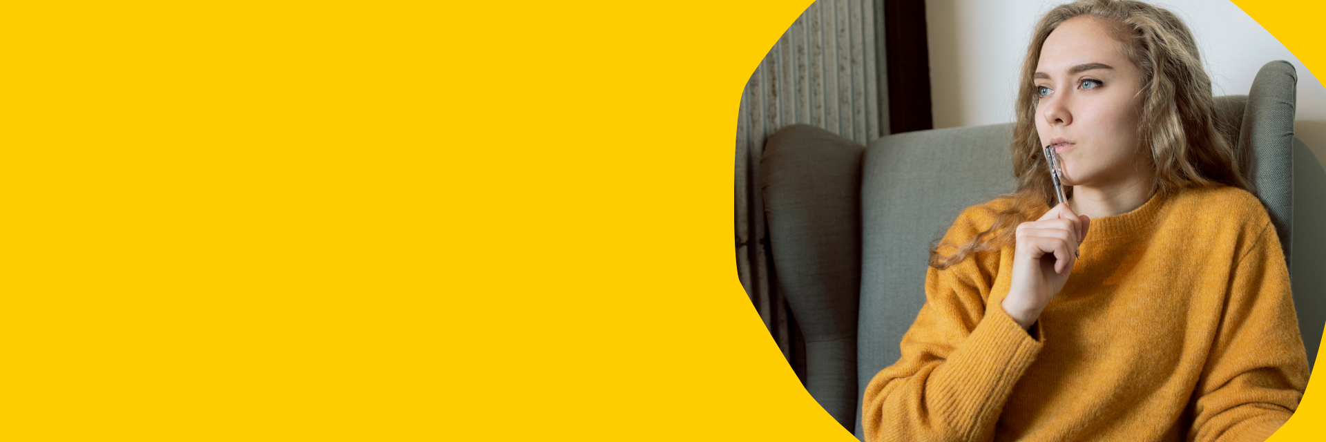a girl in a yellow jumper holding a pen to her lips while thinking