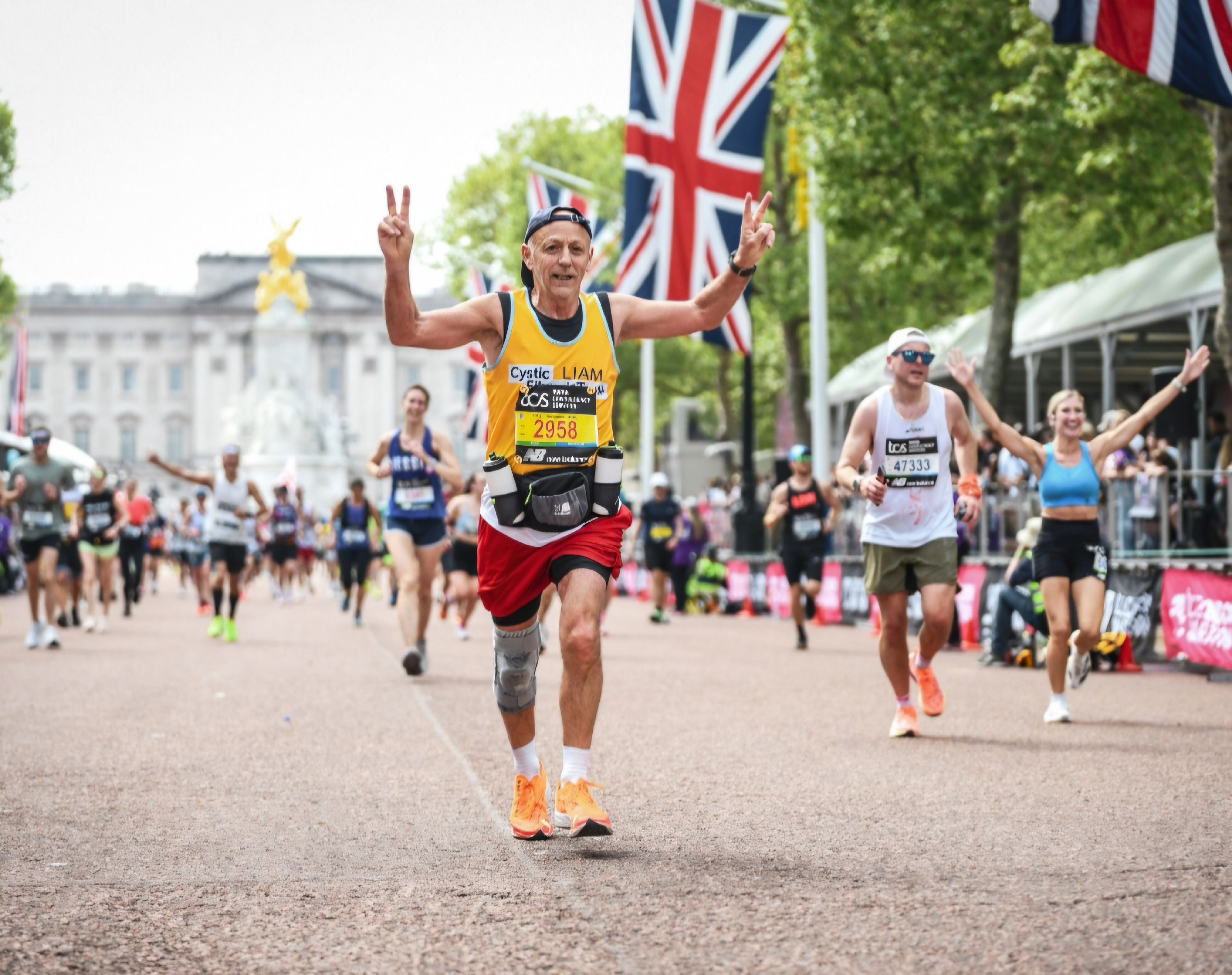 A man running in the London marathon, wearing a yellow Cystic Fibrosis Trust vest