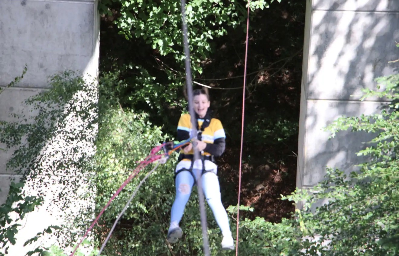 a lady in a yellow cystic fibrosis trust top doing a bungee jump