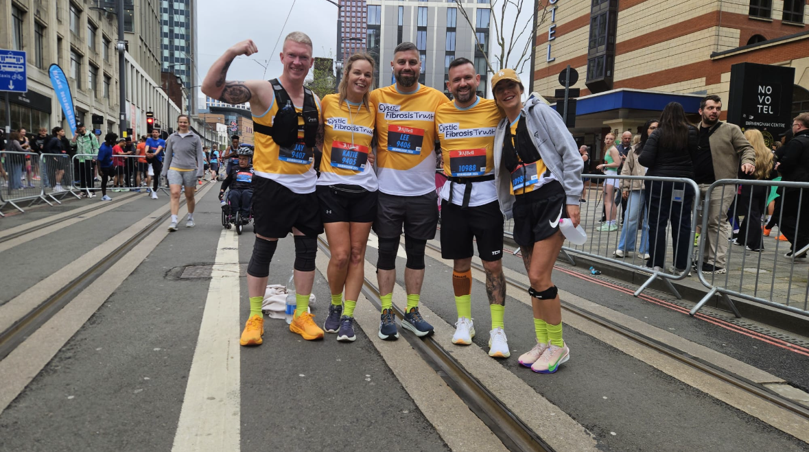 a group of people celebrating and cheering in yellow cystic fibrosis trust tops