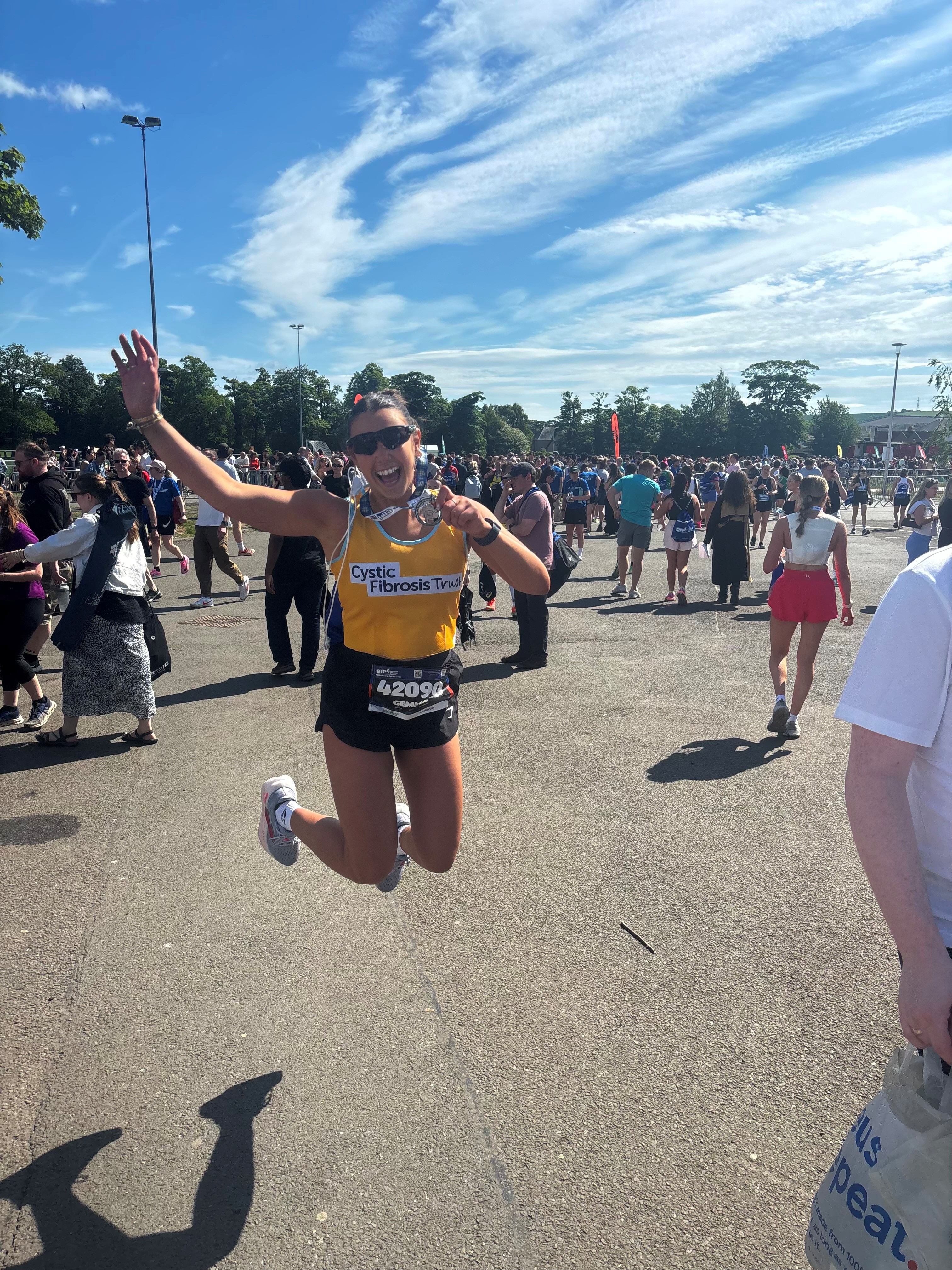 lady in cystic fibrosis trust yellow vest jumping in the air with her medal 