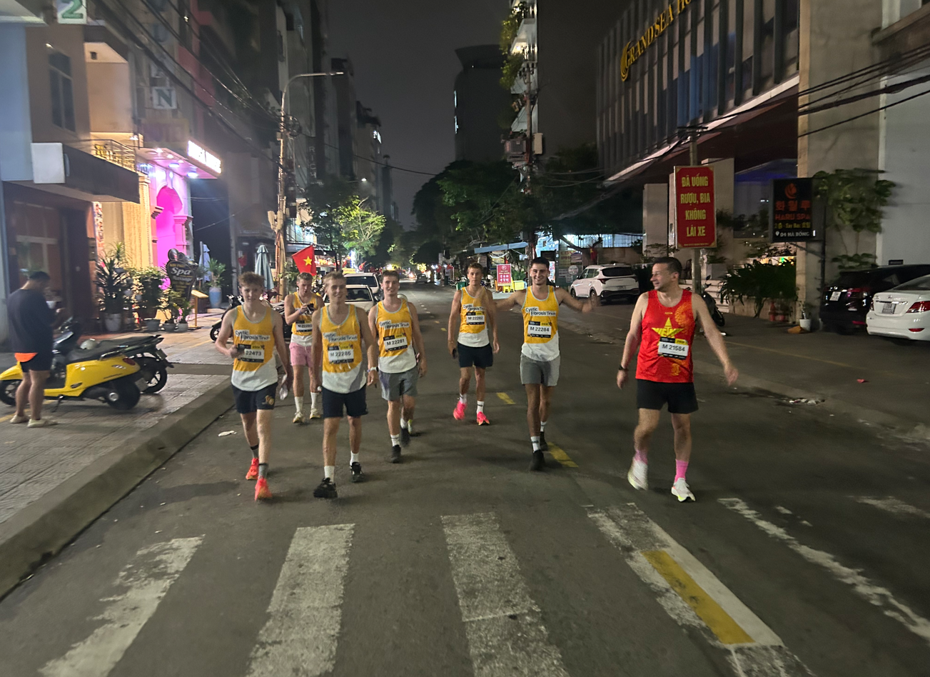 a group of 7 people wearing cystic fibrosis vests smiling and walking in a street in vietnam