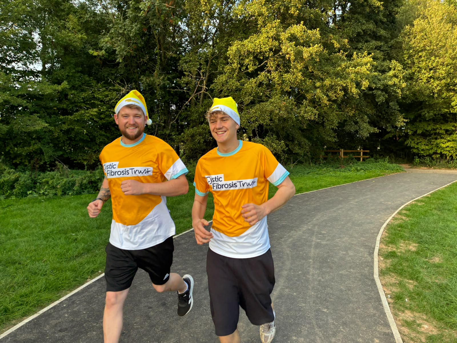 2 men running in cystic fibrosis trust yellow tops with yellow Santa hats