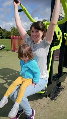 A little girl sits on a woman's lap as she exercises