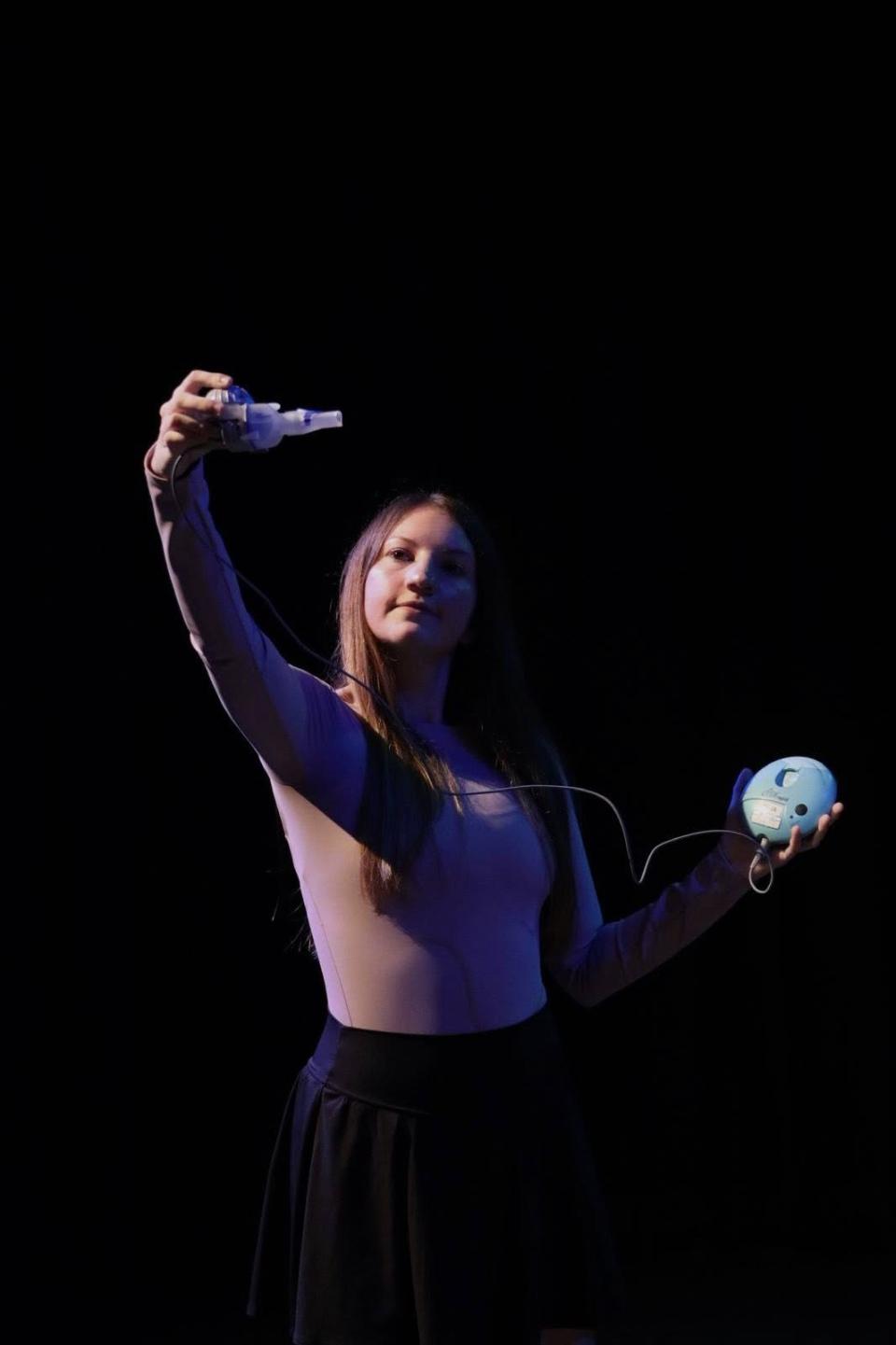 Caitlin holds her nebuliser up as part of her performance