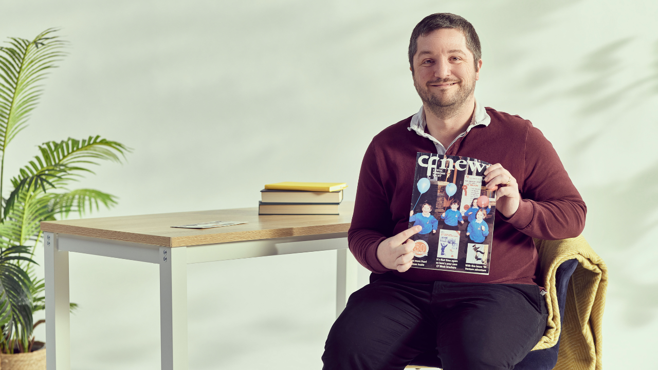 Rob sitting on a chair holding CF News magazine
