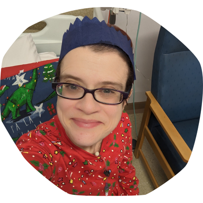 Emma in hospital, wearing a Christmas top and a paper crown