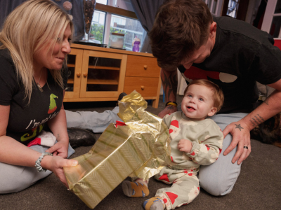 parents and baby with christmas present