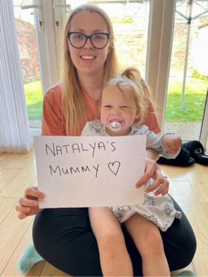 Natasha and Natalya; Natasha is holding a sign that say "Natalya's mummy"