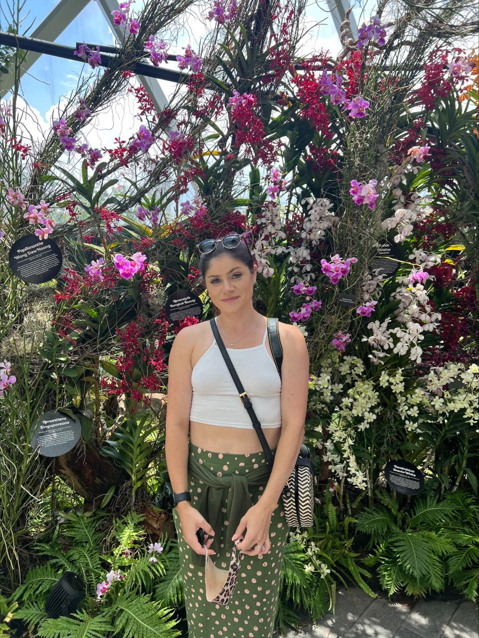 Isabelle stands in front of a wall of orchids