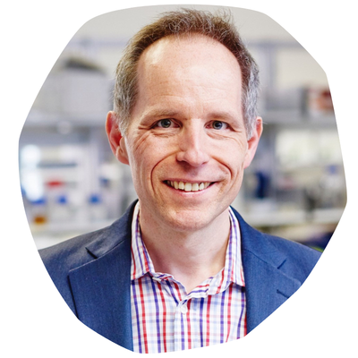 Professor Renshaw, a man with hair greying at the sides, wearing a blue suit and red and blue checked shirt