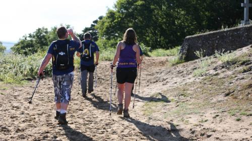 three adults walking on a rough path in the countryside