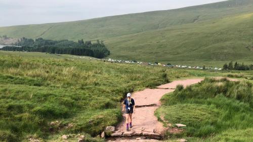 Woman walking on a path through green rolling hills