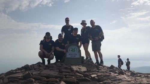 Group of adult walker standing with stone marker that says