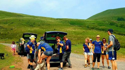 Group of walkers having a break next to two cars with rolling hills in the background
