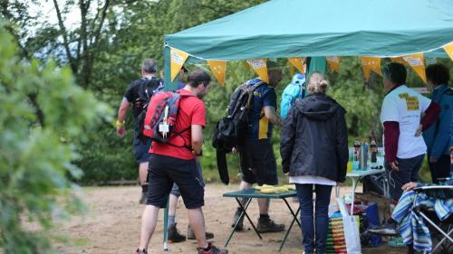 Adults in walking gear next to a gazebo with yellow bunting
