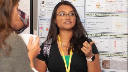 Photo of researcher with scientific poster in the background