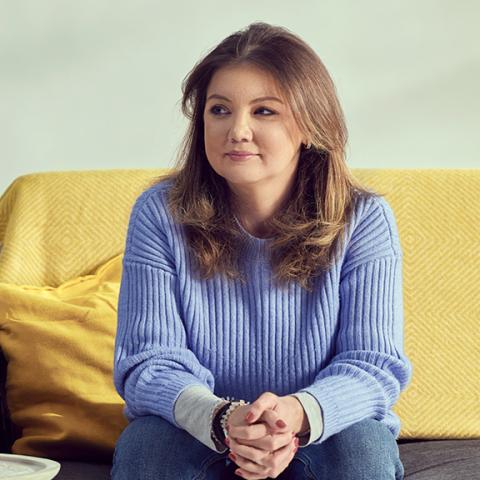 Girl in blue jumper sitting on sofa