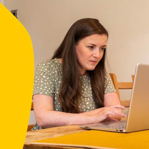 Gillian, who has CF, sitting at her computer at her kitchen table