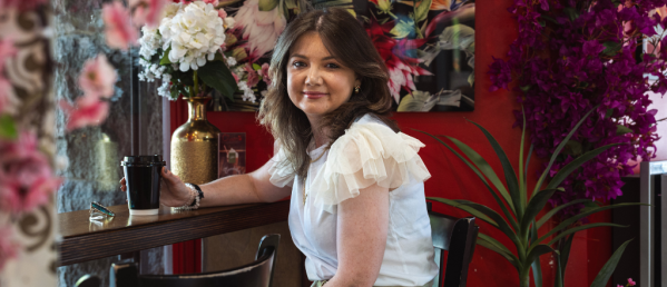 Charlotte, a young woman with CF, sitting at a coffee bar drinking coffee