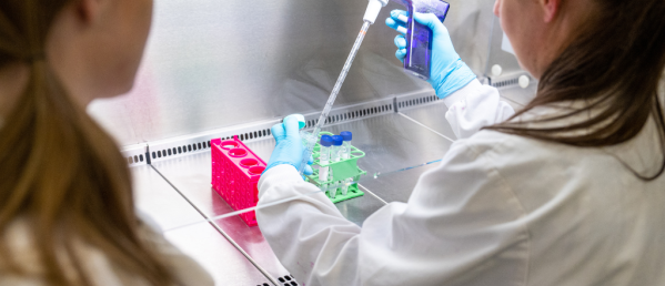 Two women in white lab coats doing science
