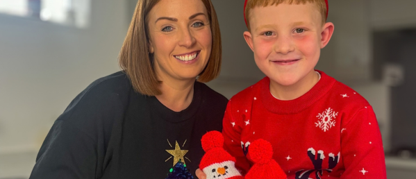 little boy and his mum; the little boy is holding two knitted snowman chocolate orange covers