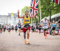 A man running in the London marathon, wearing a yellow Cystic Fibrosis Trust vest