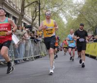 A man running, wearing a yellow Cystic Fibrosis Trust vest