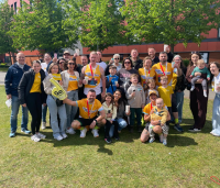 a group of people celebrating and cheering in yellow cystic fibrosis trust tops