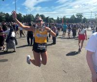 lady in cystic fibrosis trust yellow vest jumping in the air with her medal 