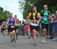 A man running in a marathon, wearing a yellow Cystic Fibrosis Trust vest
