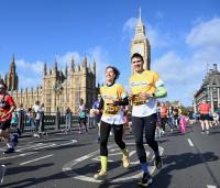 a man and woman running over the streets of London in a yellow cystic fibrosis trust top