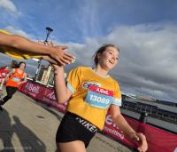 lady wearing a cystic fibrosis trust top running and high fiving a supporter