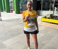 lady smiling wearing a yellow cystic fibrosis trust top, holding her race medal