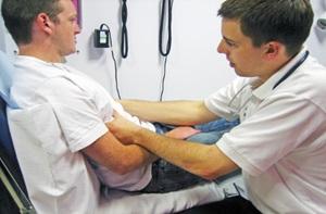 A doctor in a white shirt is pressing the chest of a patient in a similar white shirt.