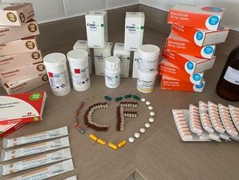 Stacks of cystic fibrosis medicines and treatments, with a lots of coloured pills arranged in a heart with pills spelling out 'CF' in the middle