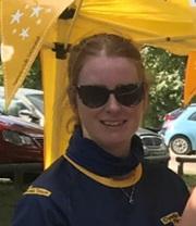 white woman wearing sunglasses in front of bright yellow bunting