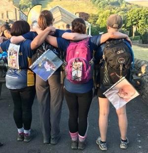 The backs four women wearing rucksacks with photos stuck to them