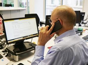 Man on phone sitting at a computer