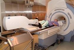 person in MRI machine with bike pedals on the bed