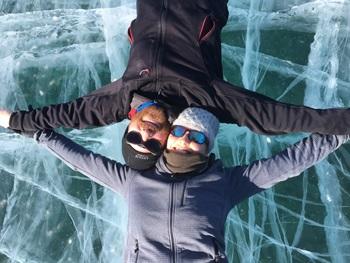 A man and a woman lie on a frozen lake smiling