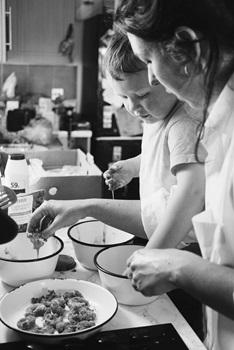 Black and white photo of mum and her young son cooking in kitchen