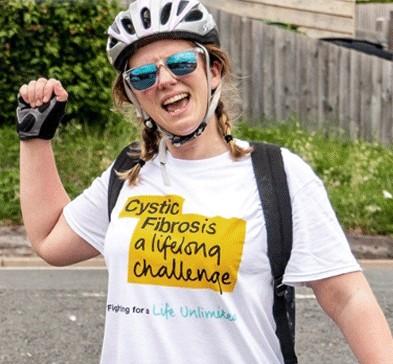 Happy young white woman in cycling helmet and Cystic Fibrosis Trust t-shirt