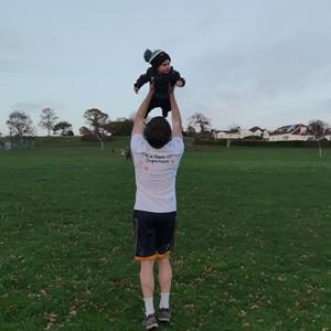 Man in activewear holding his baby aloft