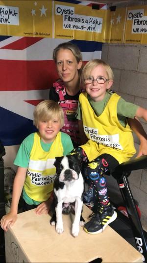 Woman with two young boys and a dog, posing on a treadmill