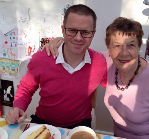 Tim with his mum, sitting at a table with a tea and cake