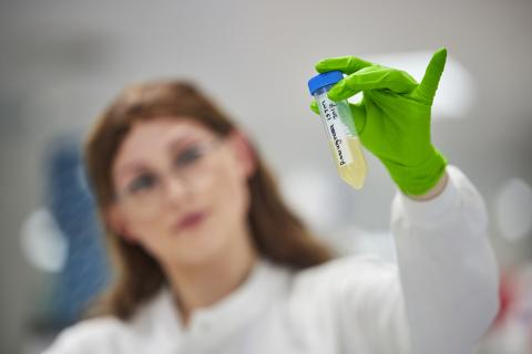 Photo of researcher holding a tube of synthetic sputum