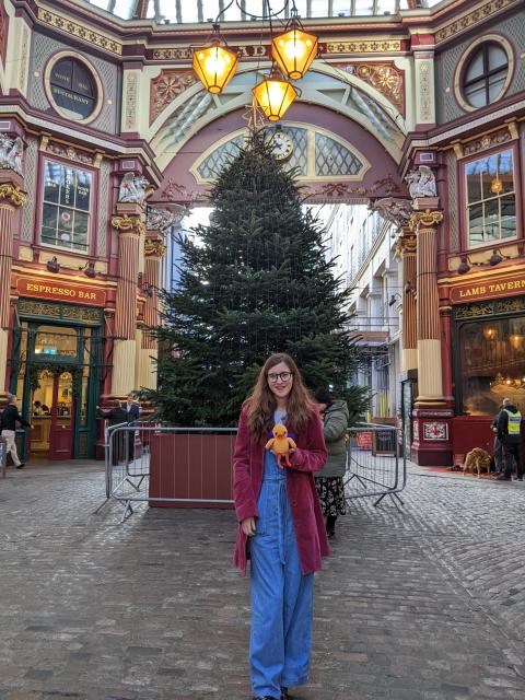 Rosie standing in front of a Christmas tree holding a crocheted duck