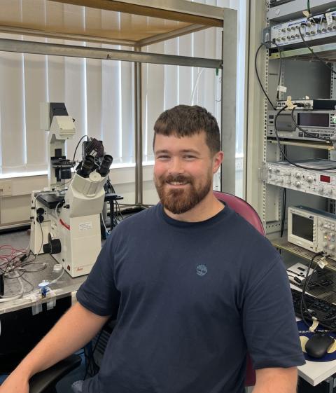 Man in a lab with lots of equipment behind him